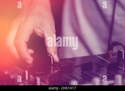 Dj plays music on party in night club with professional sound mixer panel.Hand of disc jockey adjusting the crossfader to cut music tracks in the mix Stock Photo