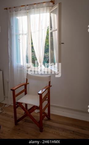 Interior of a room with a director's chair by an opened window. Stock Photo