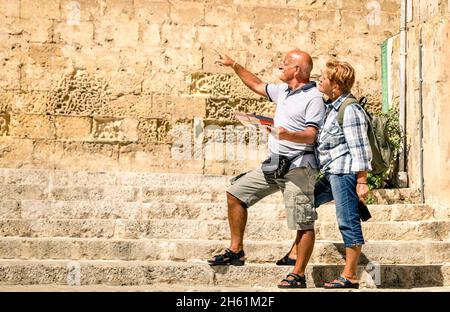 Happy senior couple exploring old town of la Valletta with city map - Concept of active elderly and travel lifestyle without age limitation Stock Photo