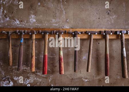 Various hammers hanging side by side on hook rack mounted on wall in industry Stock Photo