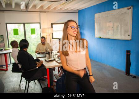 Happy female boss is being positive while her partners are haviong a serious talk Stock Photo