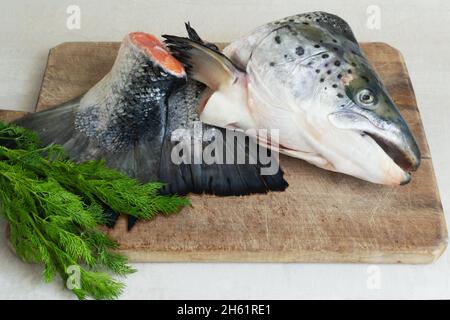 Salmon head and tail with a bunch of dill on a wooden cutting board. Cooking fish soup. Lohikeitto is a traditional Finnish and Karelian soup. Stock Photo