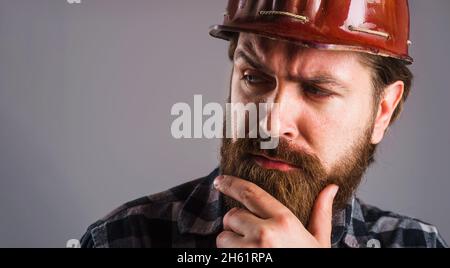 Worker in helmet. Bearded builder in hard hat. Closeup portrait of tired Engineer or architect. Copy space.