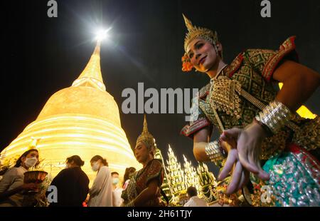 Bangkok, Thailand. 12th Nov, 2021. A dancer performs in front of Wat Saket Temple, also know as Golden Mountain during the temple and wrapped red cloth around the golden Mountain. Devotees assembled to wrap sacred red cloth around the Golden Mount chedi, signifying the start of Wat Saket festival. Before the faithful lined up for a multicultural parade consisting of lion dancers, traditional Thai dancers, students from the temples school and spiritual brahmans. Names of families and loved ones were written onto the long stretch more than hundred meters of fabric in hopes of securing good fortu Stock Photo