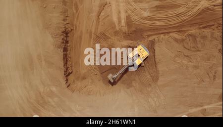 Aerial view of a digger, tracked excavator at work on a construction. Stock Photo