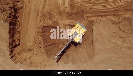 Aerial view of a digger, tracked excavator at work on a construction. Stock Photo
