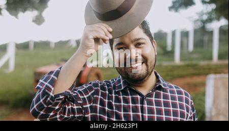 Portrait of young Latin farmer man in the casual shirt in the farm on the farm background. Stock Photo
