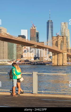 couple in front of manhattan skyline with brooklyn bridge and one world trade center,new york city,usa Stock Photo