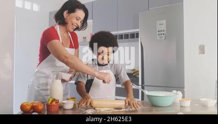 Young family cooking food in kitchen. Happy Little girl with her mother mixing batter. Mother and Little boy preparing the dough. Happy family in the Stock Photo