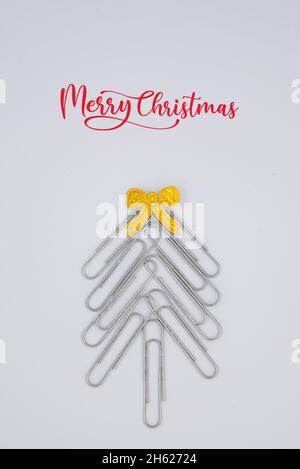 Concept merry xmas in the office. Xmas tree made of paper clips on the white background. paper clip Christmas tree. Christmas background. Stock Photo