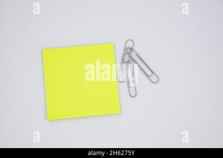 Neon yellow paper note with metal clips isolated on white Stock Photo