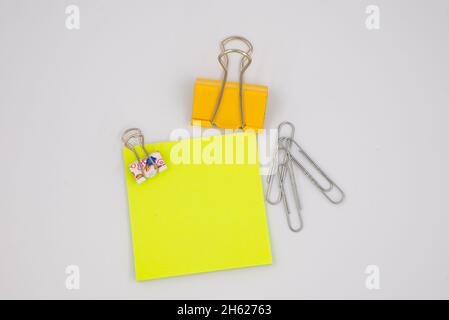 Neon yellow paper note with metal clips isolated on white Stock Photo