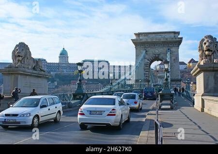 BUDAPEST, HUNGARY - NOV 11, 2019: The slow traffic on the Chain Bridge with scenic stone arch and statues of lions at the entry, on Nov 11 in Budapest Stock Photo