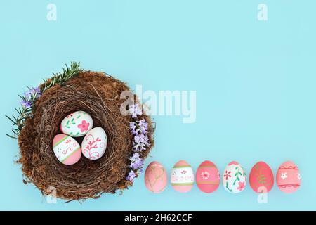 Easter egg abstract design with decorated eggs in birds nest and loose. Minimal Easter time concept on pastel blue background. Top view. Stock Photo