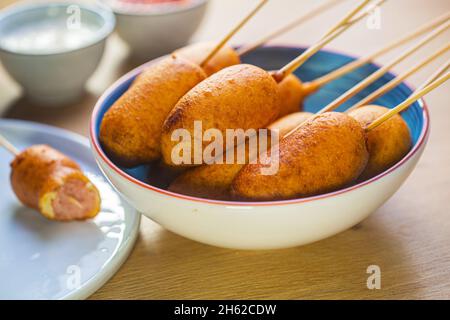 Corn dog cooked with sausage and wheat dough with the addition of corn flour, blue plate Stock Photo