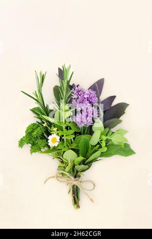 Fresh herb posy tied with string for drying and used in food seasoning and herbal medicine to treat various illnesses. On cream background, flat lay. Stock Photo