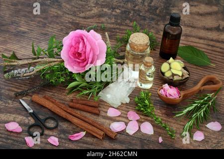 Preparing a pagan love potion with witches bundle of herbs and rose flower,  petals, oil, cinnamon, ginger spices and quartz crystal. Romantic dating Stock Photo