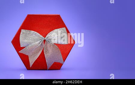 Big shiny red box with silver bow on lilac background. Present. Christmas, New Year, Mother's , Father's , International Women's Day, March 8, Birthda Stock Photo