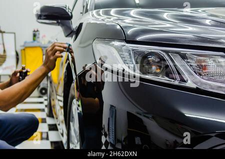 mechanic is coating ceramic glass to prevent scratches on cars.Focus headlights Stock Photo