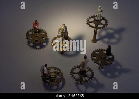Leader in the centre of a circle of cog wheels surrounded by team workers Stock Photo