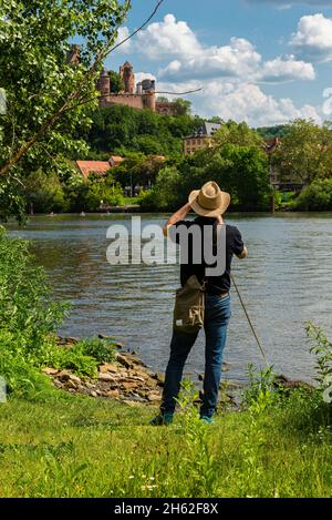 view from kreuzwertheim in bavaria over the main to wertheim castle in baden-wuerttemberg,in the foreground a man with a hat photographing the castle. wertheim on the romantic road Stock Photo