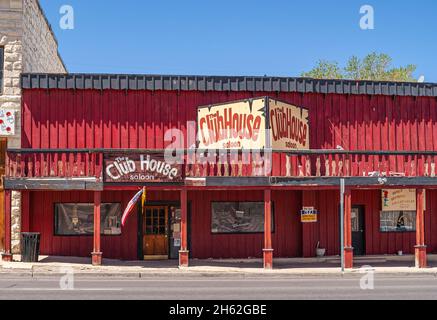 Tonopah, Nevada, US - May 16, 2011: downtown street. Red facade of The Club House saloon against blue sky. Advertisement adds colors. Stock Photo