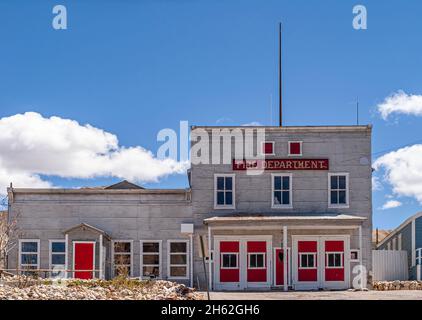 Tonopah, Nevada, US - May 16, 2011: Closeup of old Fire Department builidng is gray with red door and window features against blue cloudscape. Stock Photo