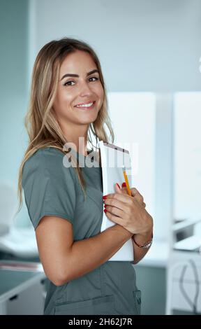 Smiling female doctor in hospital corridor. Patients consultation. Female Doctor with arms crossed Stock Photo
