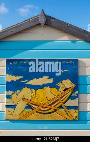 england,hampshire,hayling island,funny painting of fat lady asleep in deck chair on side of colourful beach hut Stock Photo