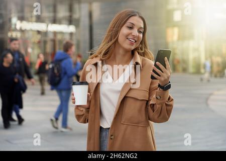 Young business people. Smartphone using. Take away coffee. Smart watch. Black friday shopping. Christmas. Blurred people background. Stock Photo