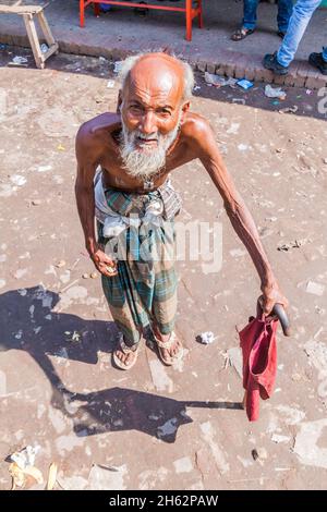 BAGERHAT, BANGLADESH - NOVEMBER 18, 2016: Old man with a stick on a bus stand in Bagerhat, Bangladesh Stock Photo