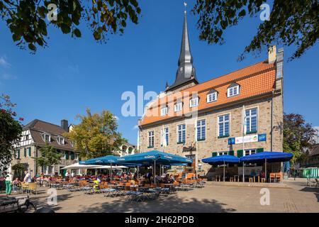 germany,ratingen,bergisches land,rhineland,north rhine-westphalia,market square,people sit in the street restaurant in front of the buergerhaus,formerly town hall,behind the catholic parish church of saint peter and paul Stock Photo