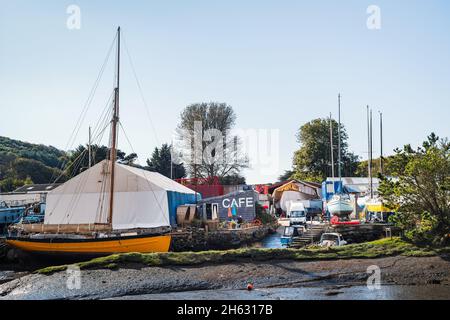 Gweek, UK - Oct 13 2021 Tourists and locals enjoy the Boatyard Cafe on the creek, in the picturesque village of Gweek in Corwall. Stock Photo