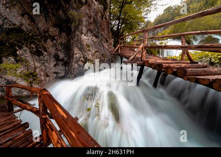 a wooden walkway surrounded by trees,waterfalls and greenery in plitvice national park,croatia Stock Photo