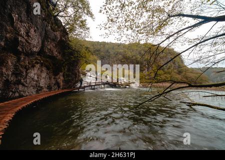 a wooden walkway surrounded by trees,waterfalls and greenery in plitvice national park,croatia Stock Photo