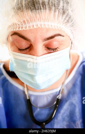 tired woman doctor wipes sweat from her forehead.. Concept of Covid-19 quarantine. Medical concept.. Stock Photo