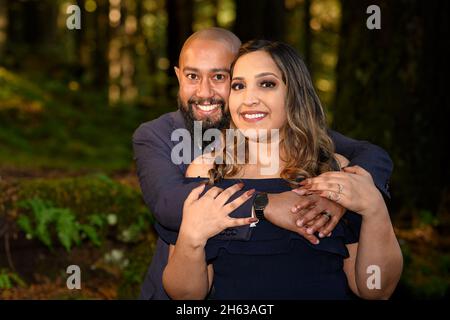 Full of love photo of an affectionate mixed race young couple holding each other in the woods in the Lynn Canyon Park, North Vancouver, British Columb Stock Photo