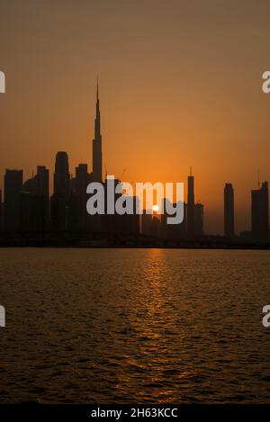Silhouette Burj Khalifa and high rise buildings at sunset Dubai Canal UAE Stock Photo