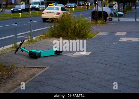 germany,berlin,august 17,2021,carelessly thrown down and overturned e-scooter on a sidewalk in the early morning in berlin,unsightly sight in berlin's city center,big problem in berlin Stock Photo