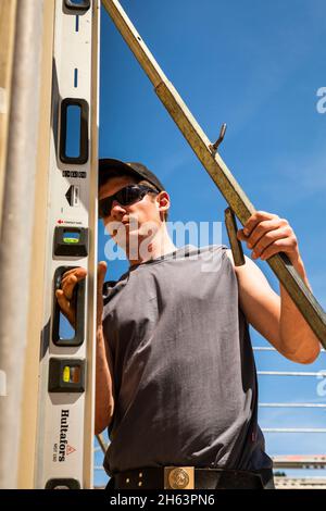 germany,bavaria,construction of a prefabricated wooden house,carpenter with spirit level, Stock Photo