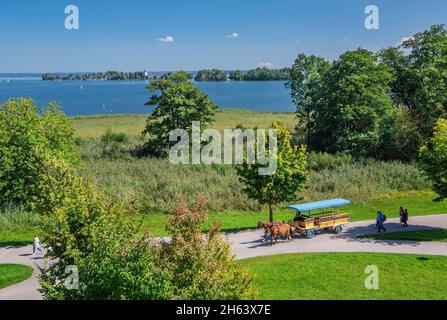 horse-drawn carriage on the island with a view of the lake to fraueninsel,municipality of chiemsee,herreninsel,chiemgau,upper bavaria,bavaria,germany Stock Photo