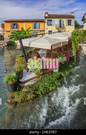 restaurant terrace with flowers on the mincio river,borghetto,district of valeggio sul mincio,mill village,po valley,verona province,veneto,italy Stock Photo