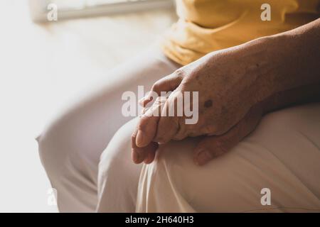 close up of two hands holding each other together at home taking care - senior and mature people hands Stock Photo