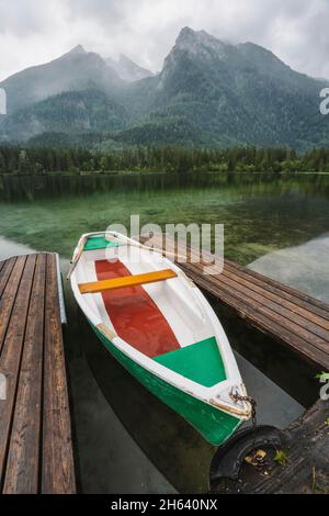 pleasure boat at pier on hintersee lake with reflection of watzmann mountain peaks. ramsau berchtesgaden bavaria,germany,europe.