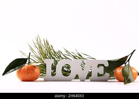 Inscription love, tangerines, fir branches on a white background.. Stock Photo