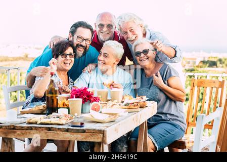 family generations enjoy and celebrate with fun all together laughing and smiling posing for a picture outdoor at home - table full of food and drinks to eat for caucasian people Stock Photo