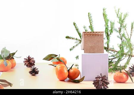 Christmas composition with spruce, tangerines, podium and notepad. Soft selective focus. Winter festive background. Stock Photo