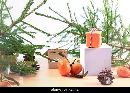 Christmas composition with spruce, tangerines, podium and notepad. Soft selective focus. Winter festive background. Stock Photo