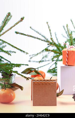 Christmas composition with spruce, tangerines, podium and notepad. Soft selective focus. Winter festive background. Stock Photo