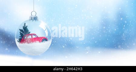 snow globe with fir tree and red car in front of a blurred background Stock Photo